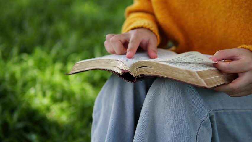 A young woman sits reading the Bible, learning about God during her quiet time seeking peaceful healing through love and His holy word.