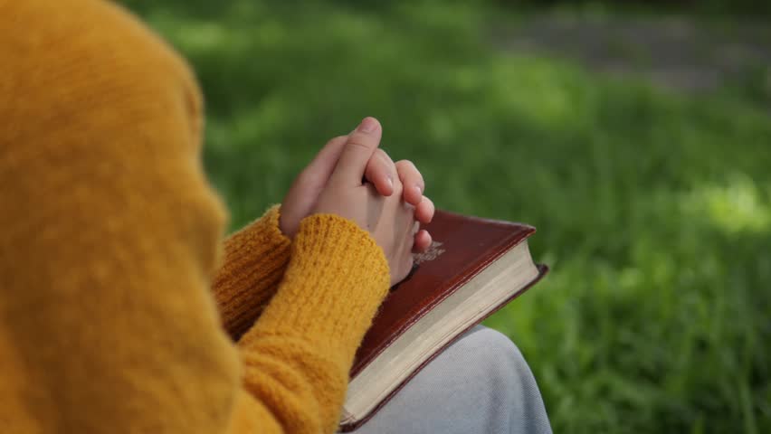 A young woman sits reading the Bible, learning about God during her quiet time seeking peaceful healing through love and His holy word.