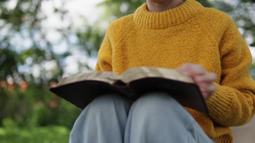 A young woman sits reading the Bible, learning about God during her quiet time seeking peaceful healing through love and His holy word.