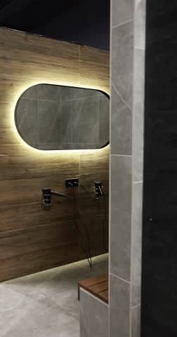 Modern gym locker room with mirror, hair dryers and bench. Camera moving left