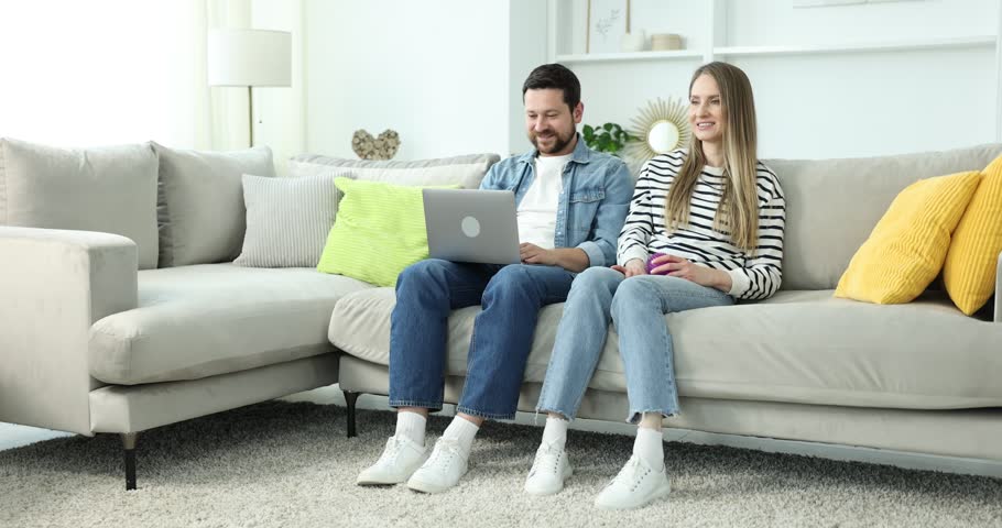 Man working on laptop and his girlfriend playing with dog at home