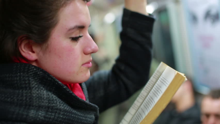 Woman reading book inside metro during her journey