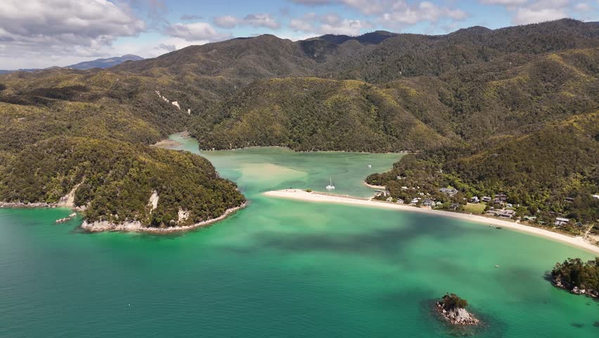 Drone view of sandy spit and sailboats anchored in clear turquoise water at Te Pukatea Bay in Abel Tasman National Park, New Zealand. Aerial, copy space