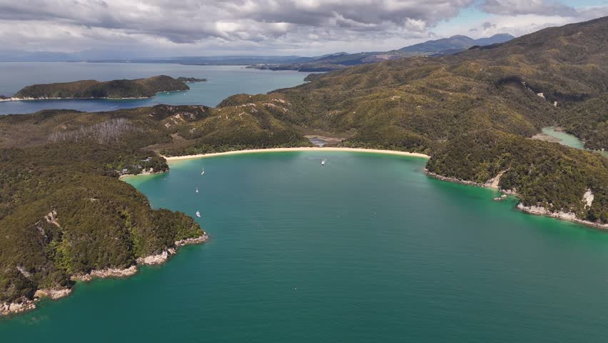 High angle wide aerial view of boats anchored in the turquoise waters of Anchorage Bay in Abel Tasman National Park.