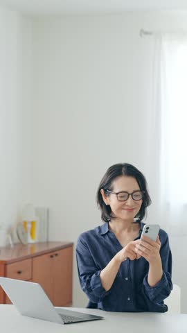 A middle-aged woman smiling while looking at her smartphone.
