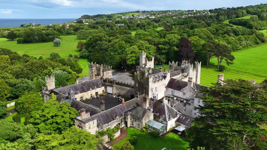 Howth castle estate on Howth peninsula near Dublin, aerial view, orbiting drone shot of Howth castle in Ireland, medieval Irish castle ruins, travel in Ireland