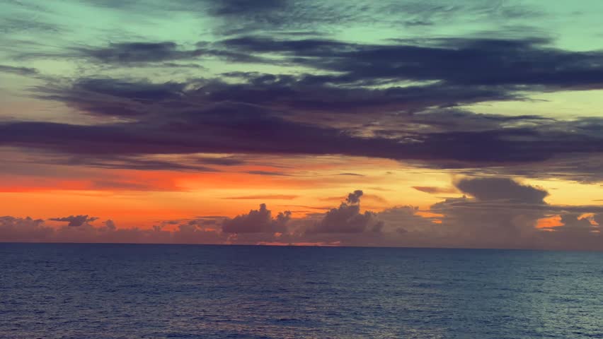 Vibrant sunset over calm sea with dramatic clouds in the sky