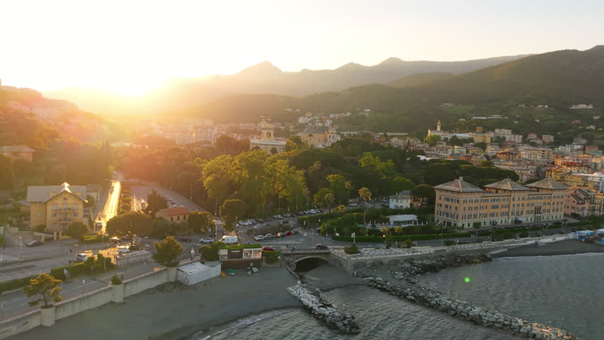 Aerial view of Arenzano coastline and town with sun setting behind hills in Liguria