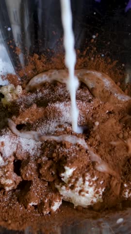 Baker or chocolatier preparing chocolate bonbons add milk to cocoa to make a cocoa and cottage cheese dessert