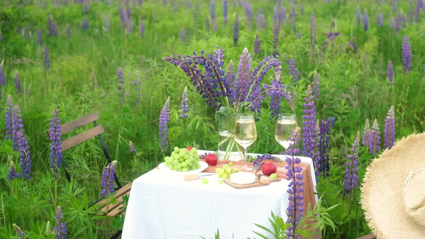 Table setting with food and wine among lavender flowers
