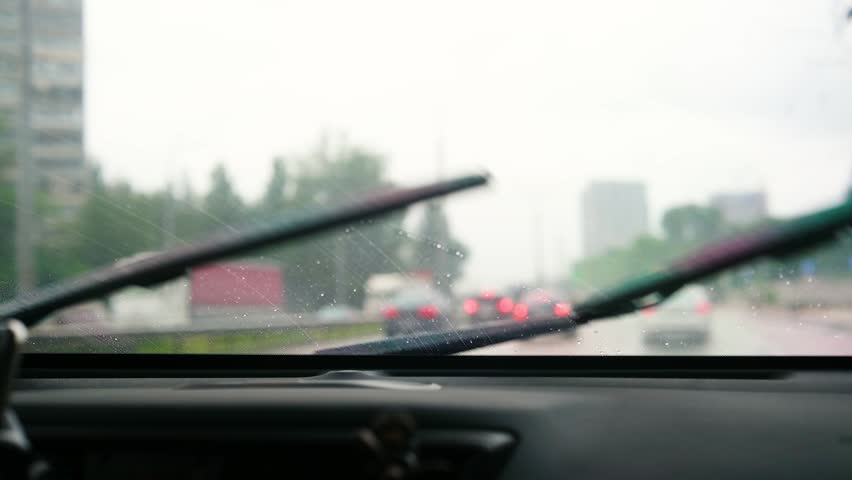 Cars driving on a wet road seen through a rainy window