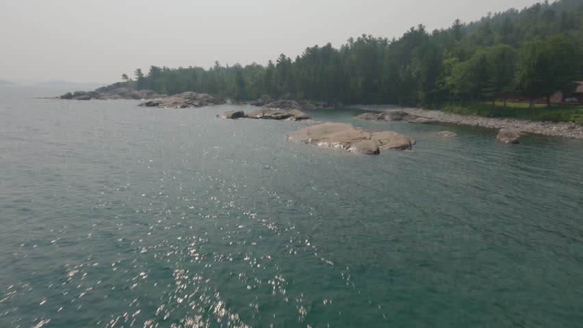 Aerial view flying over the rocky coastline of lake superior on a hazy summer day in marquette, michigan