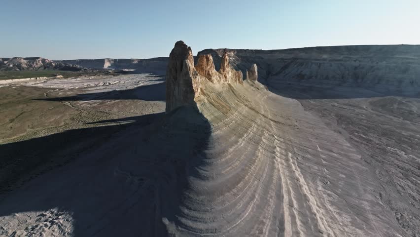 Aerial perspective captures rocky formations with layered textures in a vast desert landscape, showcasing natural geological features and shadows