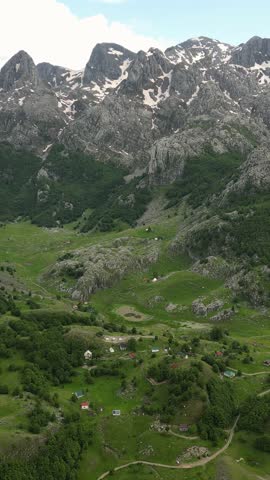 Aerial view of the stunning kuci mountains in montenegro. Beautiful green valley with a small village nestled below majestic rocky peaks