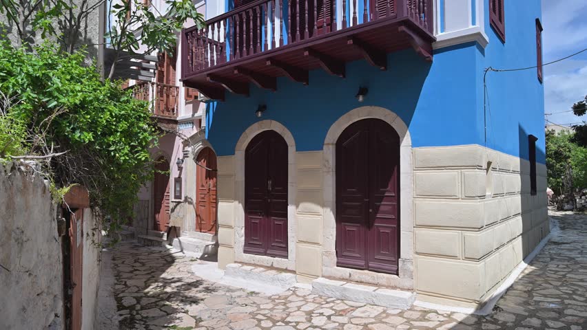 Picturesque narrow street with traditional blue and white architecture in Kastellorizo, Greece. An upward view of a historic home with balconies