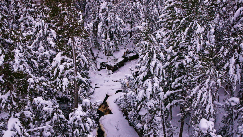 Drone view of a river snaking through a blanket of fresh winter snow.