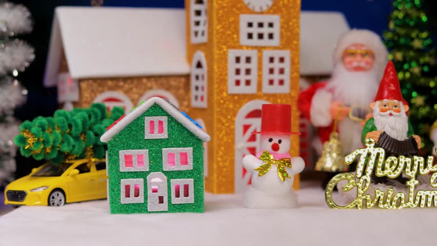 In the Christmas town, in front of the colorful houses, there are snowmen with letters and Santa Claus with a gnome