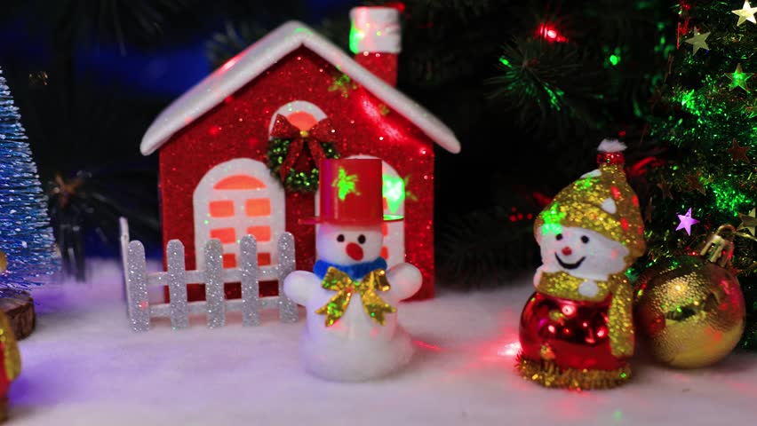 Near the houses there are two snowmen with a yellow ball and Santa Claus on a sleigh