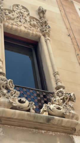 Vertical close-up video of an ornate Modernist architectural facade in Reus, Tarragona, Catalonia, Spain. Decorative stone carvings, floral motifs, sculpted columns, and wrought-iron balcony details showcase the elegance of Catalan Modernism. Historic architecture, cultural heritage, craftsmanship, tourism, and European architectural art concept.