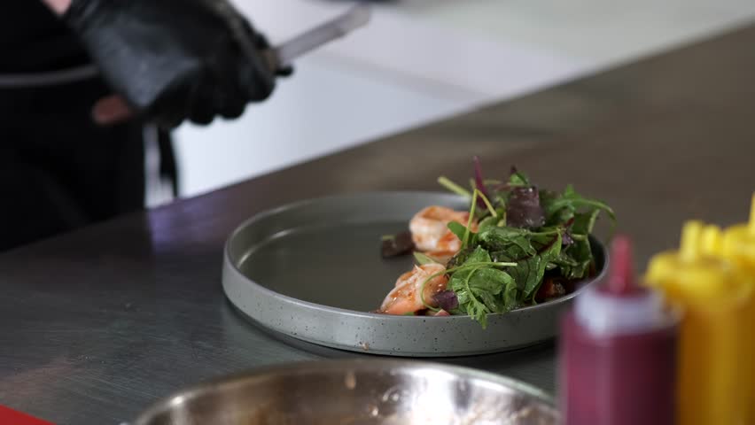 A person in a kitchen preparing food on a plate