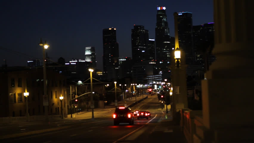 Smooth dolly shot along a bridge at night revealing the iconic glowing downtown Los Angeles skyline. 