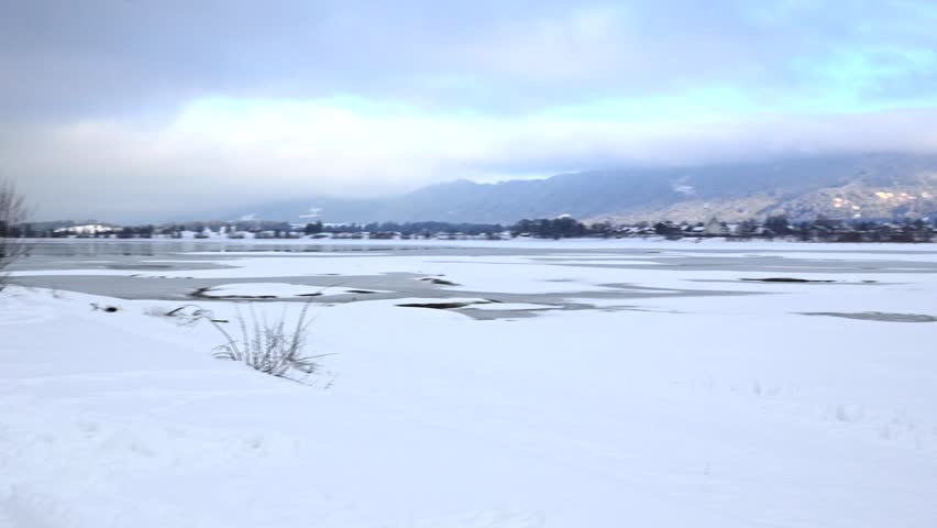 Frozen Lake Ice Channels with Snow Covered Mountains and Pine Forest in Winter