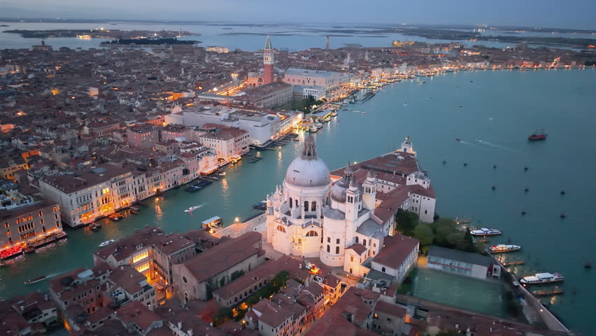 Venice aerial sunset over lagoon, boats gliding past basilica santa maria della salute, pastel sky casting. Italy