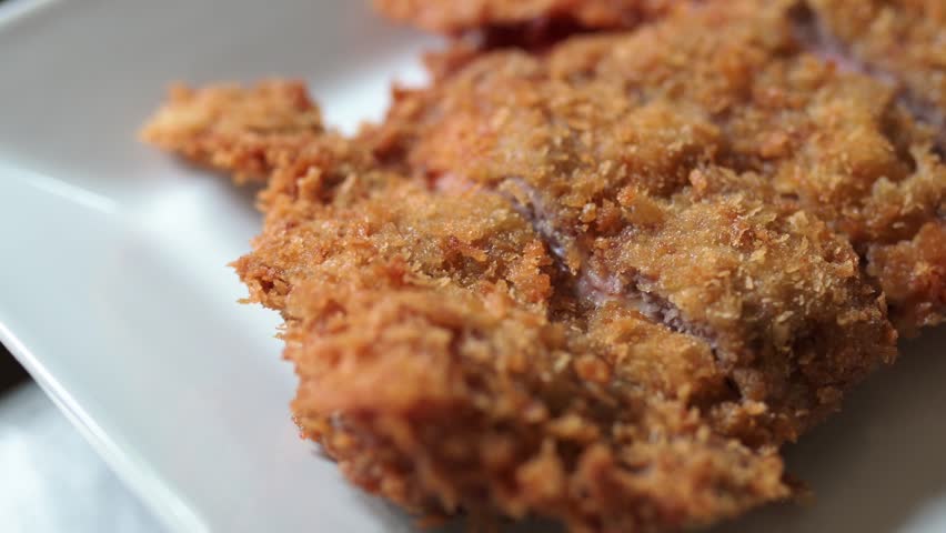 Delicious traditional spanish cachopo, a breaded veal fillet stuffed with ham and cheese, presented on a plate in extreme close up