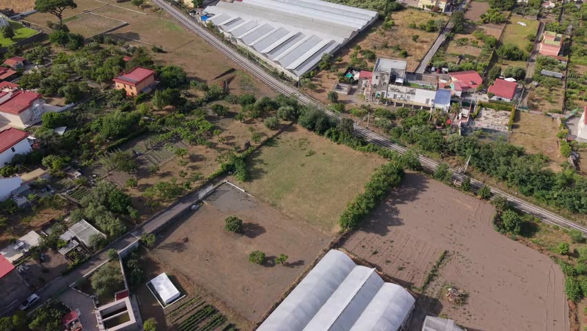 Greenhouses, farmland and railway crossing a rural area in Torre del Greco, Campania, Italy, showcasing agriculture, horticulture and commercial crop production