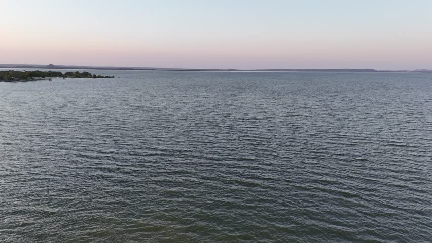Low water hover then slow rise over giant Texas Hill Country lake with peninsula coming into view