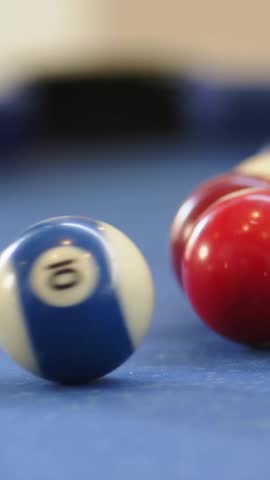 Vertical video: Rolling red 1 ball on blue felt table after white cue ball striking, copy space. Billiards, collision, closeup, macro, blur, bokeh, vertical video