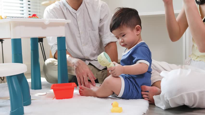 Young family shares joyful moments on floor. Parents smile warmly while playing with child. Child laughs happily in parents
