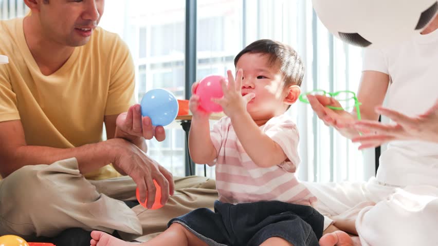 Young family shares joyful moments on floor. Parents smile warmly while playing with child. Child laughs happily in parents