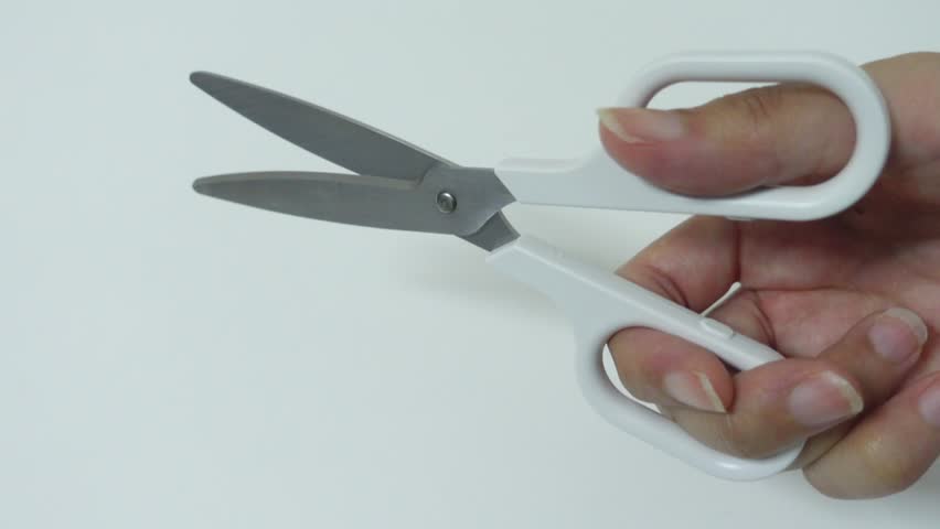 Close-up of hand holding scissors on white background, craft studio footage