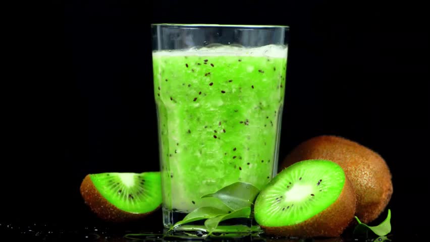 Kiwi smoothie is poured into a glass next to whole and sliced kiwi fruit. The footage shows a fresh, healthy