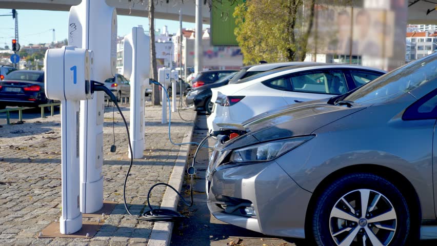 Electric Cars Rows Comprising Various Parked at Urban Charging Area. Clean Eco Friendly Transport Vehicles Replenishing High Voltage Batteries Simultaneously. Electric Car Charging at Cable Plug 4k