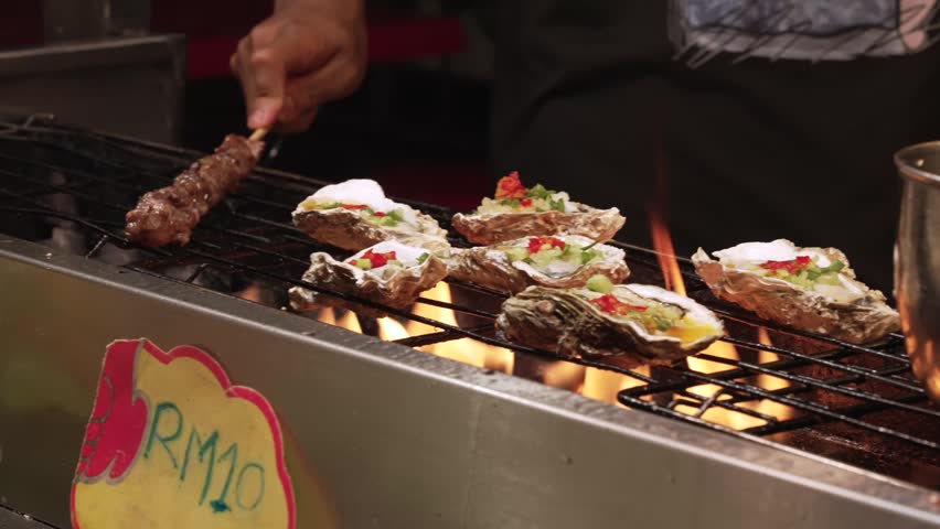 Close up of Grilled Oysters with Chili and Spring Onion on BBQ Grill Malaysian Street Food Night Market