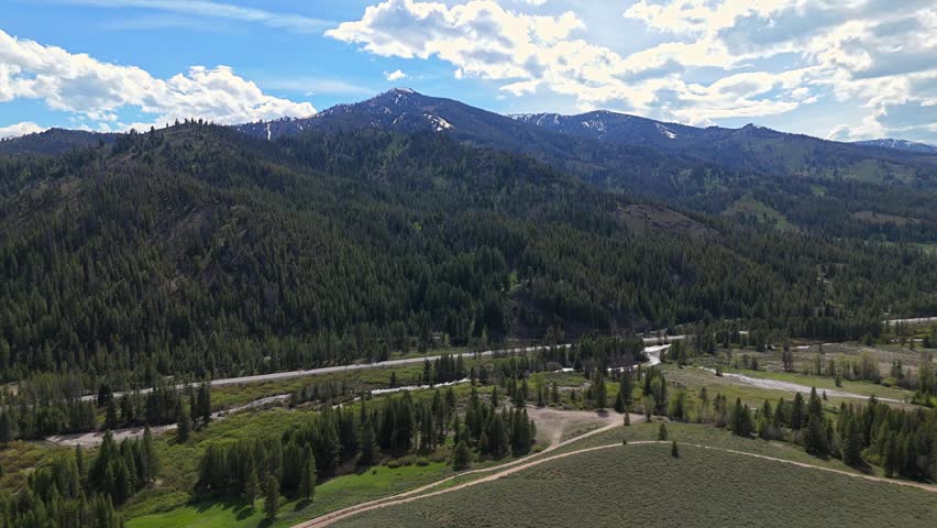 High aerial orbit shot of Sawtooth Mountains near the Sawtooth Scenic Byway, Idaho on a sunny day in spring.