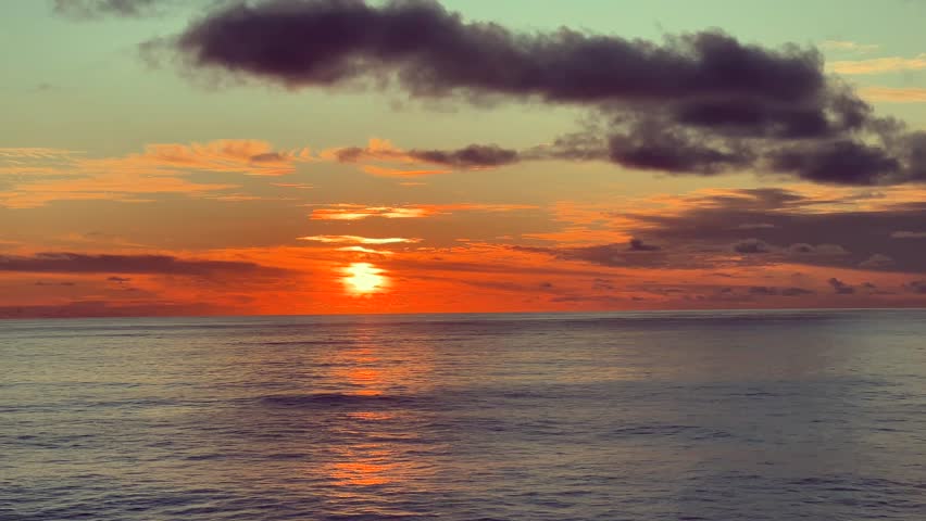 Colorful sunset sky over calm ocean waves with vibrant clouds reflecting light on the water surface