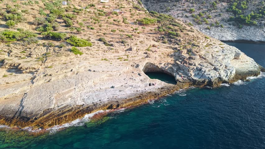 Aerial view of the famous natural rock pool filled with emerald green water right next to the deep blue Aegean Sea. Giola Lagoon, Thasos, Greece