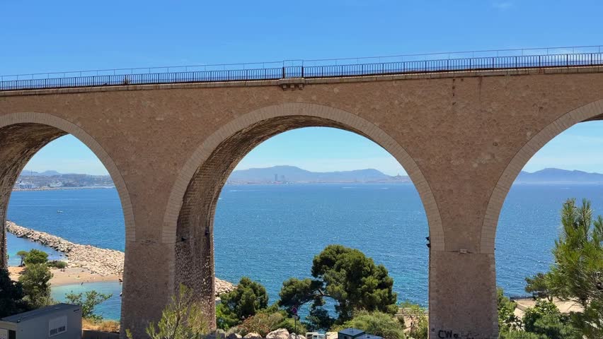 Scenic view of Vallon des Auffes bridge in Marseille overlooking the Mediterranean Sea on a bright sunny day. Iconic coastal landmark with blue water and clear summer sky.