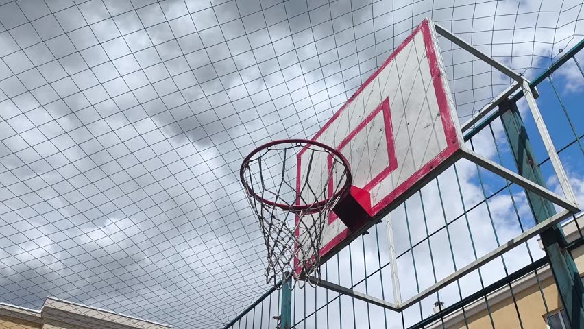 Slow motion close-up of a basketball spinning around the rim of a basketball hoop without scoring and then flying toward the camera. Dramatic sports action highlighting near miss, precision and competition.