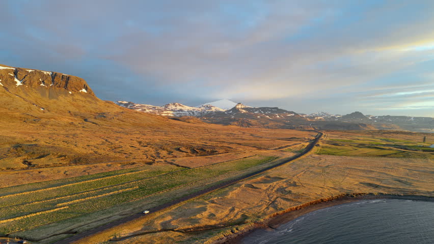 Aerial approach over highland lagoons toward snow-dusted mountains. Iceland