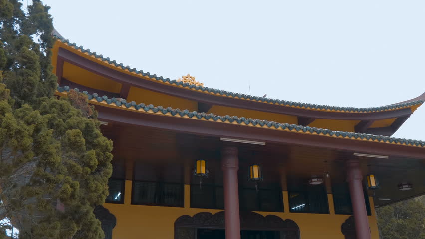 Pagoda in the Trúc Lâm Zen Monastery largest in Da Lat, Vietnam features traditional Asian tiled roof with upturned corners and orange walls stands peacefully in the garden
