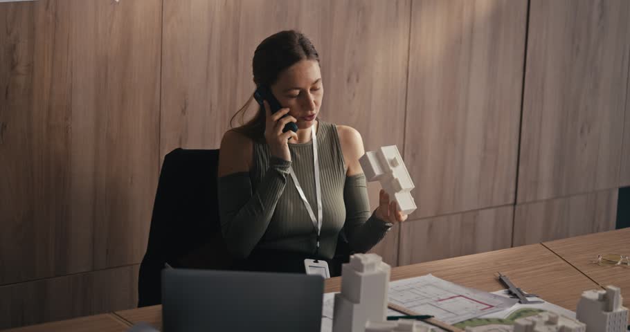 Businesswoman speaking on phone while reviewing documents at a conference table