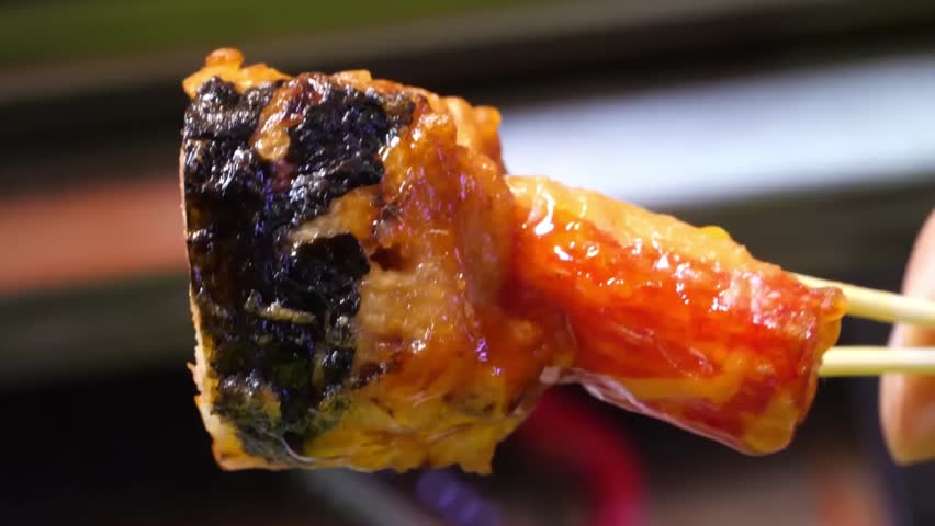 Close-up of popular Korean street food, Eomuk (fish cake) or Odeng, skewered and glazed with a savory red sauce. This traditional snack, made from minced fish and starch, is a staple at South Korean n