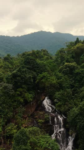 Vertical screen Scenic Waterfall With Visitor Trail In Phong Nha Carved Walkway And Railings Beside Cascading Tiers, Leafy Canopy, Rocky Steps, Approachable Attraction With Dramatic Karst