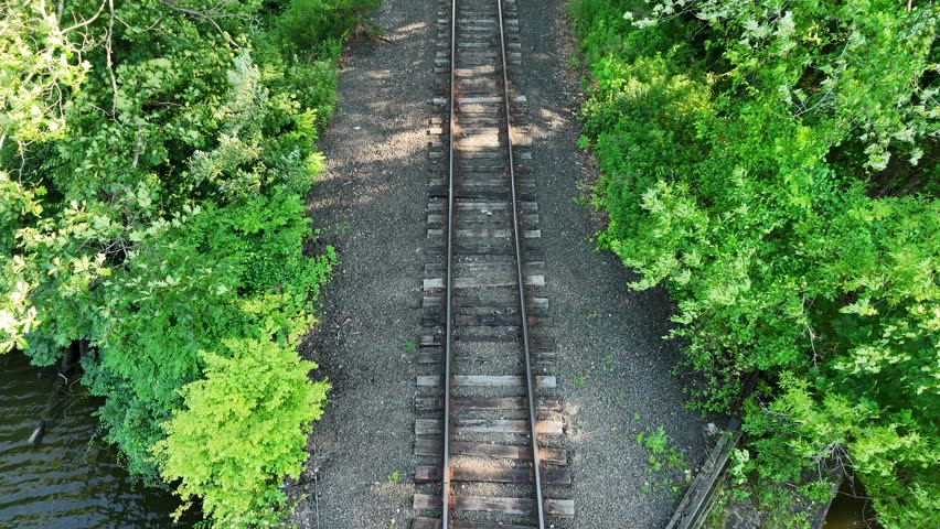 Scenic high-angle aerial drone footage capturing the historic charm of New Milford, Connecticut, located in Litchfield County. The video showcases the beautiful New England suburban landscape, featuring the winding Housatonic River, lush green hillsides, and the classic downtown village green area with its traditional architecture and local streets. Perfect for regional tourism marketing, commercial real estate videos, New England travel documentaries, autumn or summer seasonal concepts, and small-town American lifestyle stock media.