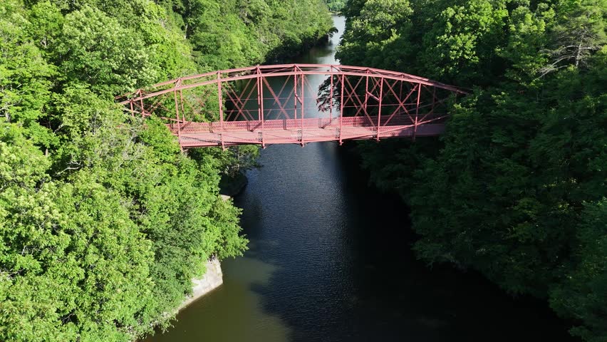 Scenic high-angle aerial drone footage capturing the historic charm of New Milford, Connecticut, located in Litchfield County. The video showcases the beautiful New England suburban landscape, featuring the winding Housatonic River, lush green hillsides, and the classic downtown village green area with its traditional architecture and local streets. Perfect for regional tourism marketing, commercial real estate videos, New England travel documentaries, autumn or summer seasonal concepts, and small-town American lifestyle stock media.
