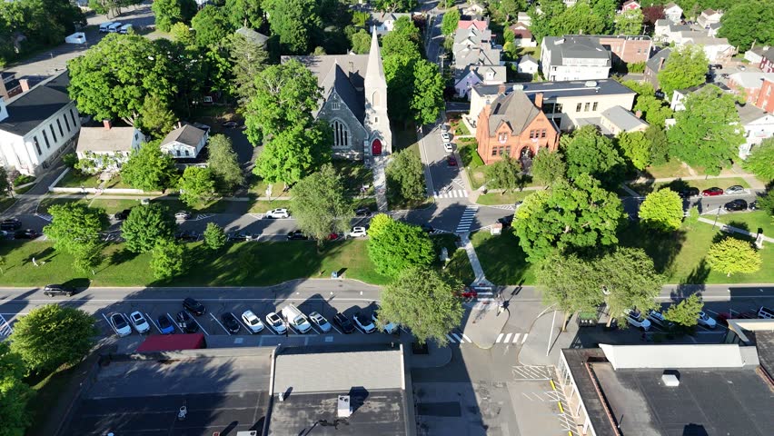 Scenic high-angle aerial drone footage capturing the historic charm of New Milford, Connecticut, located in Litchfield County. The video showcases the beautiful New England suburban landscape, featuring the winding Housatonic River, lush green hillsides, and the classic downtown village green area with its traditional architecture and local streets. Perfect for regional tourism marketing, commercial real estate videos, New England travel documentaries, autumn or summer seasonal concepts, and small-town American lifestyle stock media.
